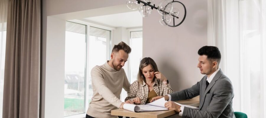 A couple consults with a real estate agent in a modern indoor setting, reviewing property documents.