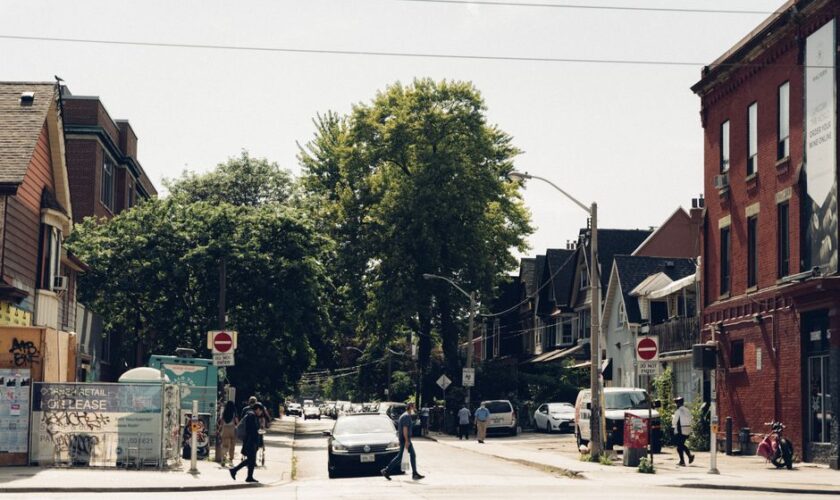 A lively urban street scene with people crossing a pedestrian lane under clear daylight.