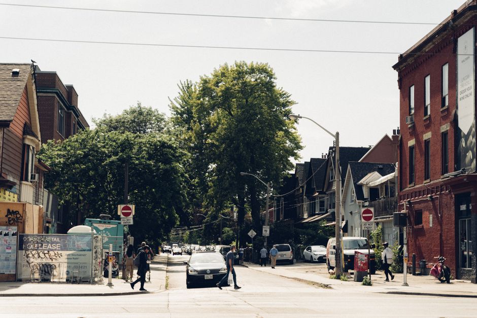 A lively urban street scene with people crossing a pedestrian lane under clear daylight.