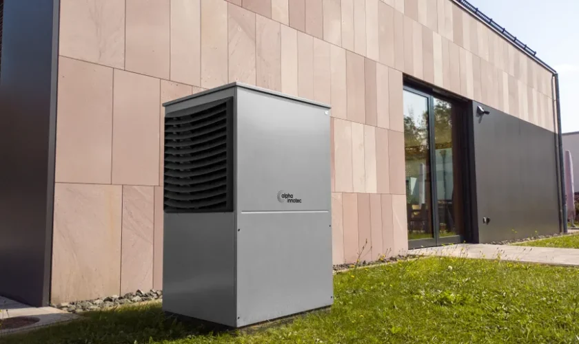 A modern heat pump unit installed outdoors next to a contemporary building, showcasing renewable energy technology.