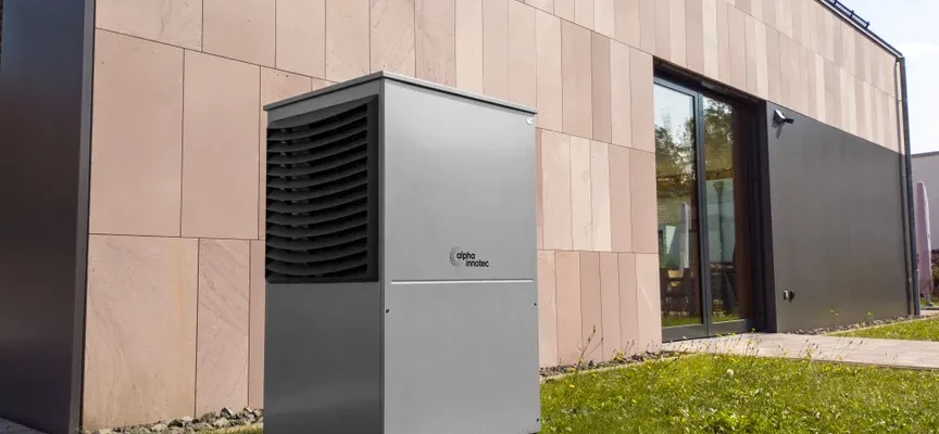 A modern heat pump unit installed outdoors next to a contemporary building, showcasing renewable energy technology.