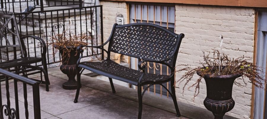 A stylish outdoor terrace featuring a decorative metal bench and potted plants, perfect for urban relaxation.
