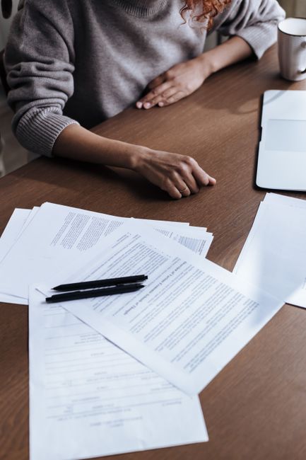 A woman sits at a desk reviewing paperwork, representing diversity in a professional setting.