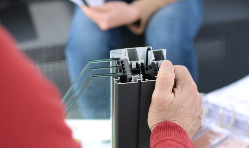 Close-up of hand holding an aluminum window frame sample, ideal for construction themes.