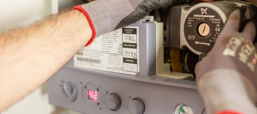 Close-up of hands adjusting a boiler system with precise instrumentation, showing maintenance work.
