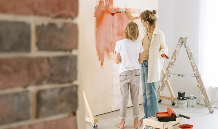 Mother and son collaborate on painting a wall during a home renovation project.