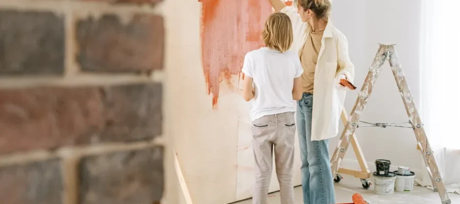 Mother and son collaborate on painting a wall during a home renovation project.