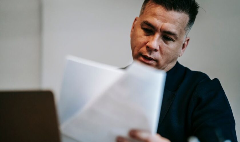 Professional man intently reviewing paperwork at his workstation indoors.