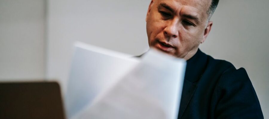 Professional man intently reviewing paperwork at his workstation indoors.