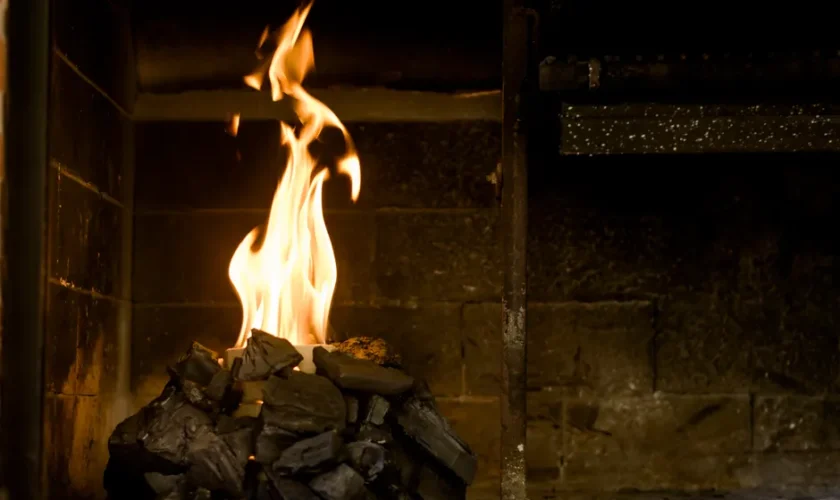 Relaxing indoor setting with burning coals and flames producing warmth and light.