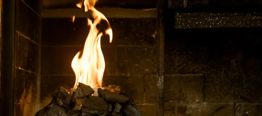 Relaxing indoor setting with burning coals and flames producing warmth and light.
