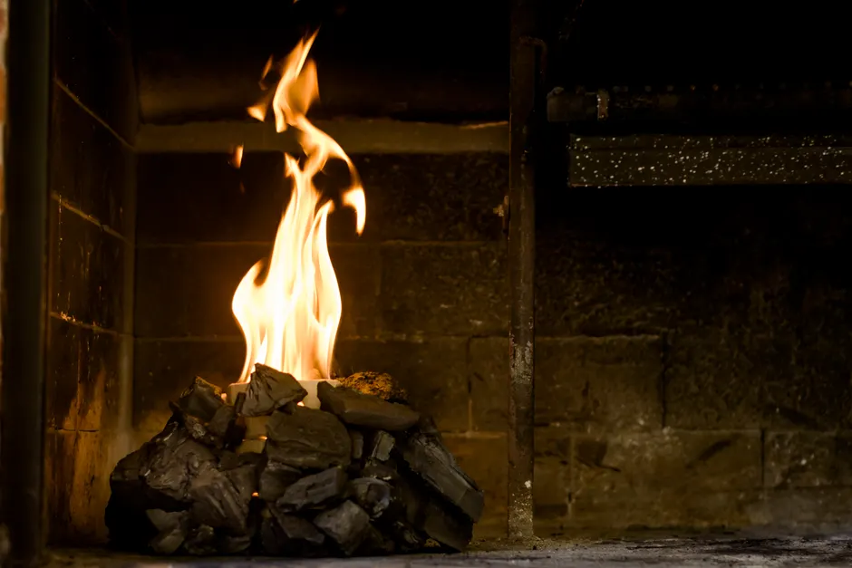 Relaxing indoor setting with burning coals and flames producing warmth and light.