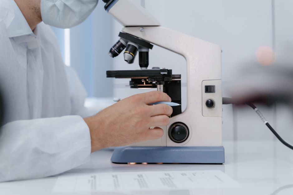 Researcher analyzing samples with a microscope in a lab setting.