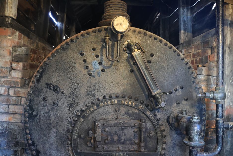 Rustic industrial boiler with intricate metalwork and brick surroundings in Marston, England.