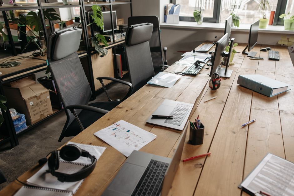 Spacious co-working office with wooden desks, laptops, and modern chairs.