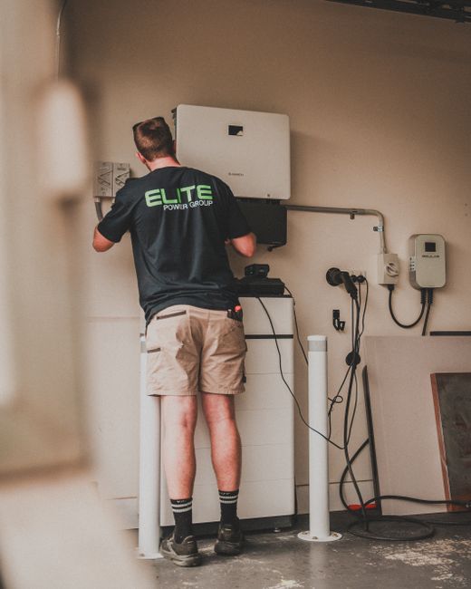 Technician working on the installation of a residential solar battery system indoors.