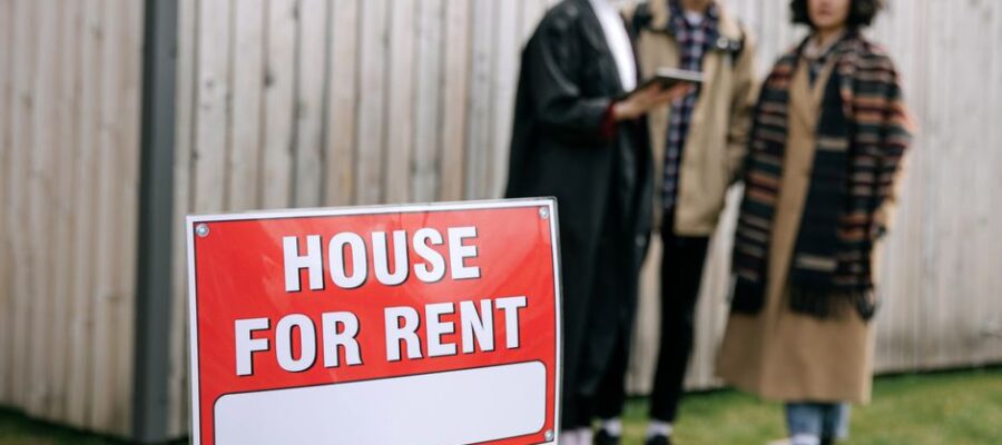 Three adults examining a house for rent sign outdoors, depicting diverse and inclusive interest in rental properties.
