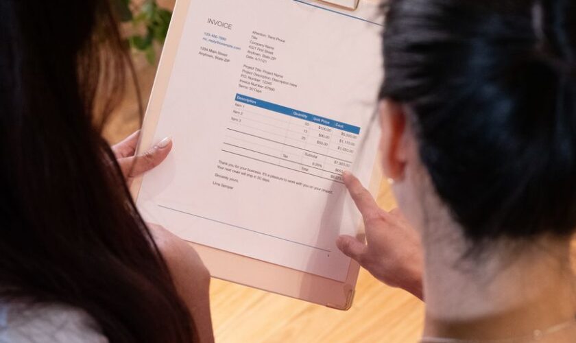 Two individuals reviewing an invoice together in a modern office setting.