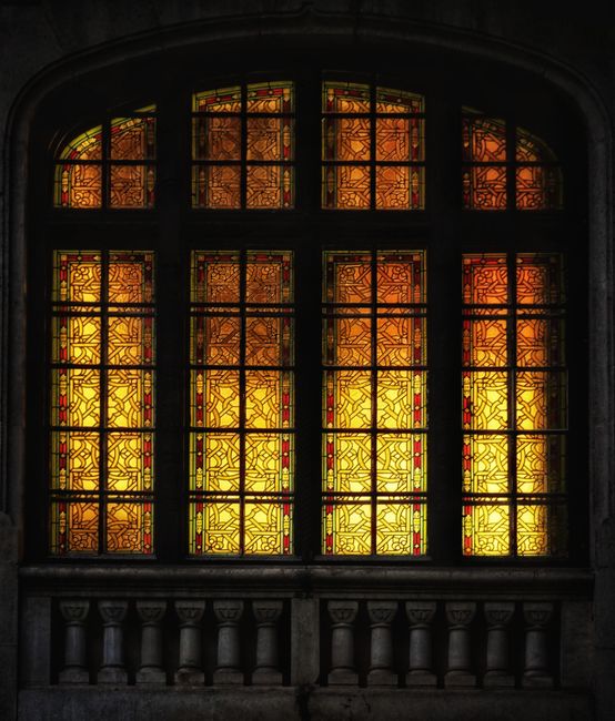 A beautifully ornamented stained glass window radiating warm light in Brasov, Romania.