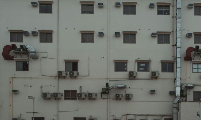 A building facade covered with air conditioning units and ducts illustrating urban architecture.