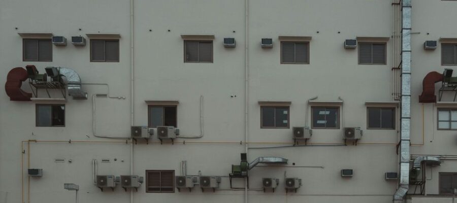 A building facade covered with air conditioning units and ducts illustrating urban architecture.