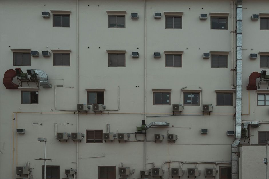 A building facade covered with air conditioning units and ducts illustrating urban architecture.