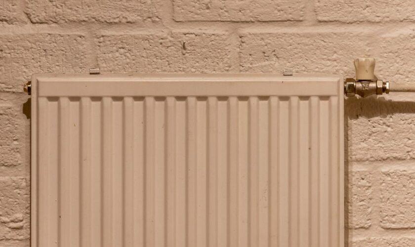 A clean white radiator mounted on a textured brick wall, indoors and well-lit.