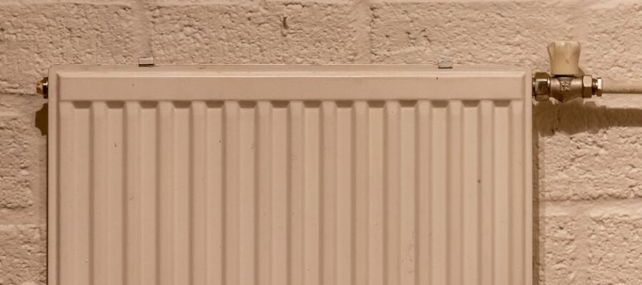 A clean white radiator mounted on a textured brick wall, indoors and well-lit.