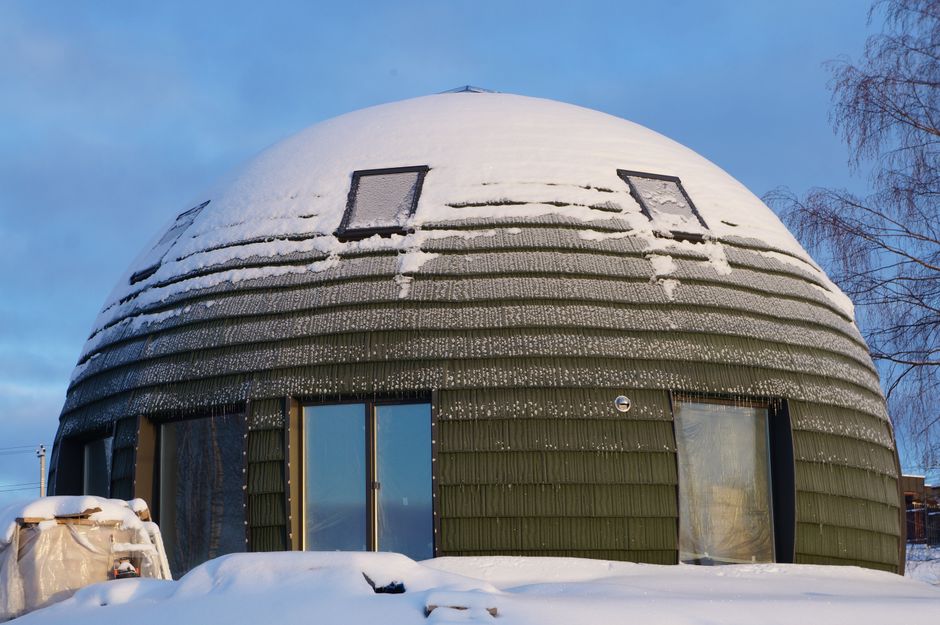 A distinctive dome-shaped house with snow under a blue winter sky, illustrating unique architecture.