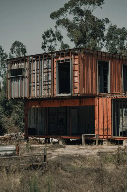 A rustic, container house structure set in a natural, wooded environment.