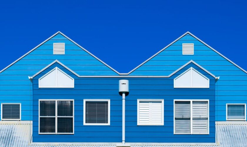A vibrant blue house facade with windows and a clear sky, showcasing modern architecture.