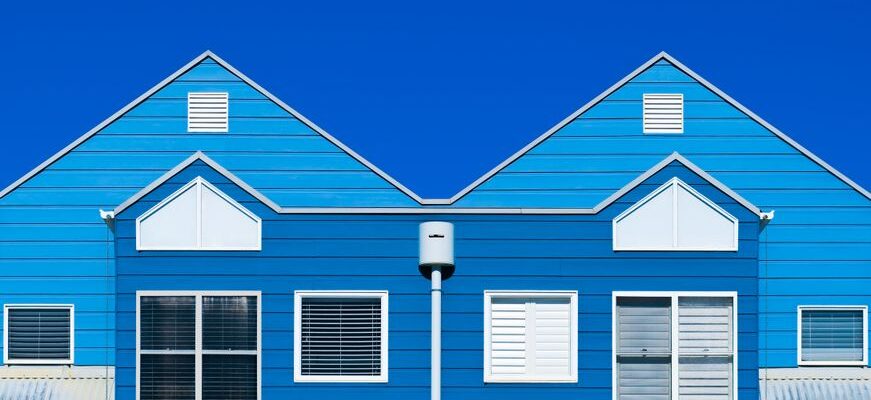 A vibrant blue house facade with windows and a clear sky, showcasing modern architecture.