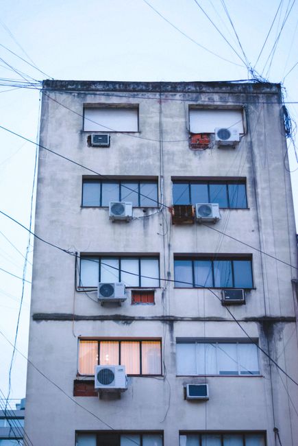 A weathered apartment building in Buenos Aires with multiple air conditioners.