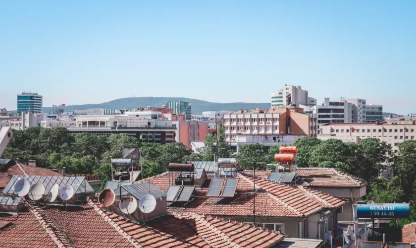 Aerial cityscape of Gaziantep, Turkey, showcasing urban rooftops with solar panels under a bright summer sky.