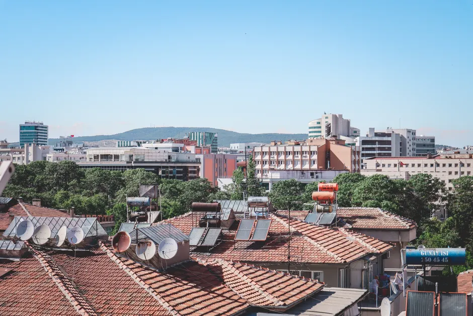 Aerial cityscape of Gaziantep, Turkey, showcasing urban rooftops with solar panels under a bright summer sky.