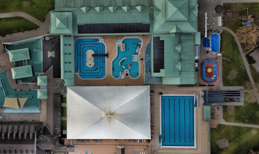 Aerial shot of a modern aquatic center featuring multiple swimming pools and green rooftop.