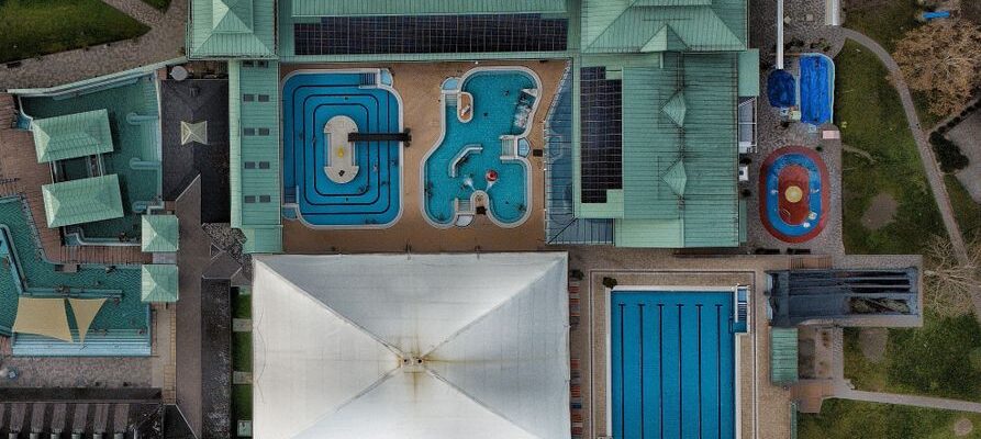 Aerial shot of a modern aquatic center featuring multiple swimming pools and green rooftop.