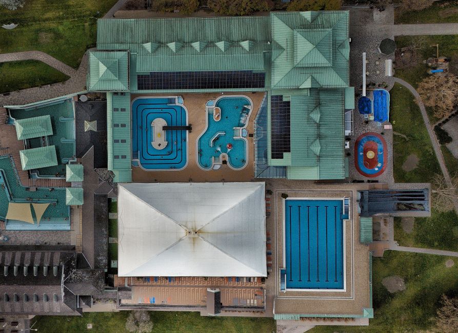 Aerial shot of a modern aquatic center featuring multiple swimming pools and green rooftop.