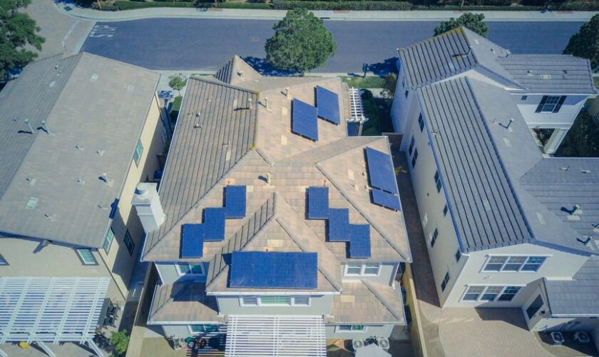 Aerial view of suburban homes equipped with solar panels in a sunny neighborhood.