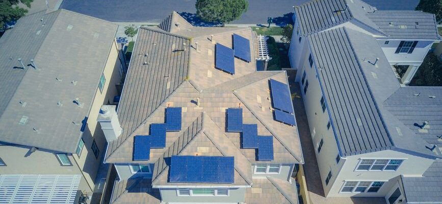 Aerial view of suburban homes equipped with solar panels in a sunny neighborhood.