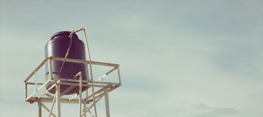 An industrial water tank atop a metal frame against a clear sky, showcasing infrastructure design.