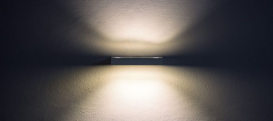 Artistic wall lamp casting soft shadows, creating a minimalist ambiance in a dim setting.