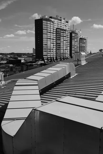 Black and white photograph of modernist buildings with rooftop air ducts, under a clear sky.