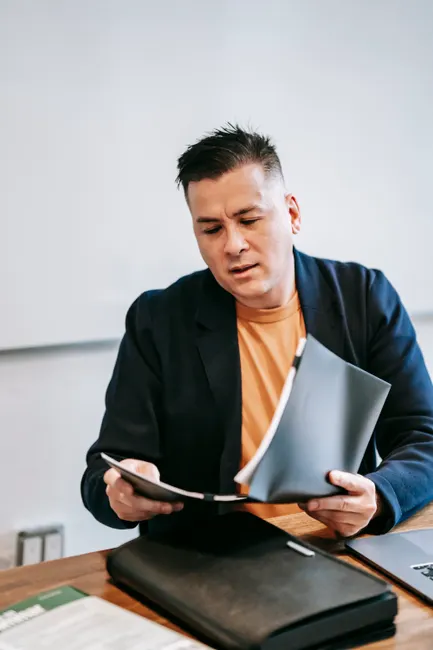 Businessman in a suit reviewing documents at an office desk, focused on work.