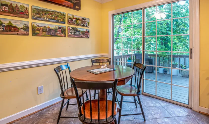 Charming dining area with paintings, table, and sliding door opening to a balcony.