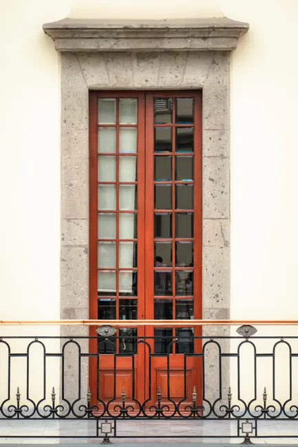 Classic wooden door with decorative iron railing on a traditional building facade.