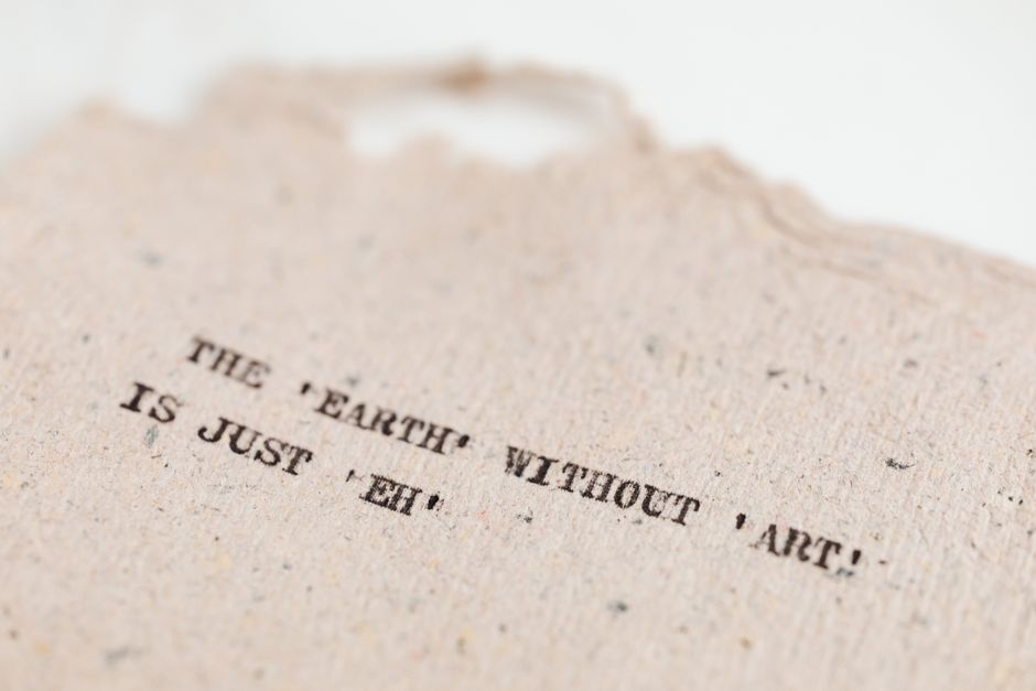 Close-up of a motivational art quote on a handmade textured paper background.