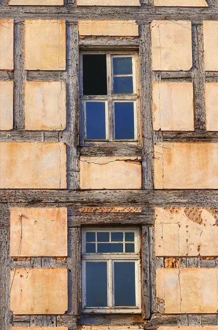 Close-up of weathered timber-framed building facade with vintage windows.