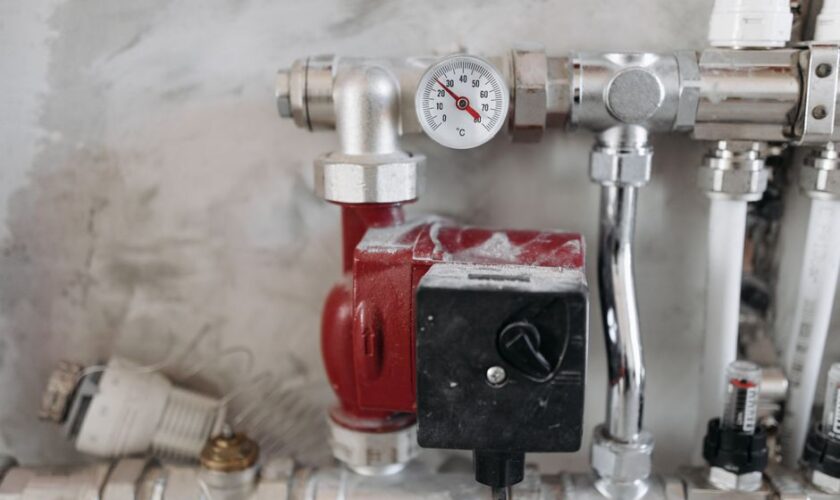 Close-up view of an industrial plumbing system featuring a pressure gauge and steel pipes.