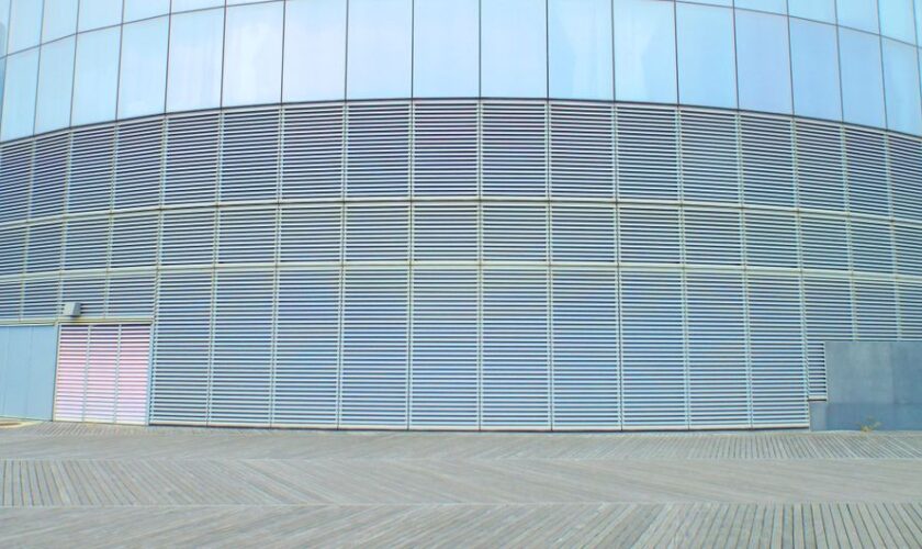 Contemporary glass building wall with aluminum solar facade shading panels on clear sunny day